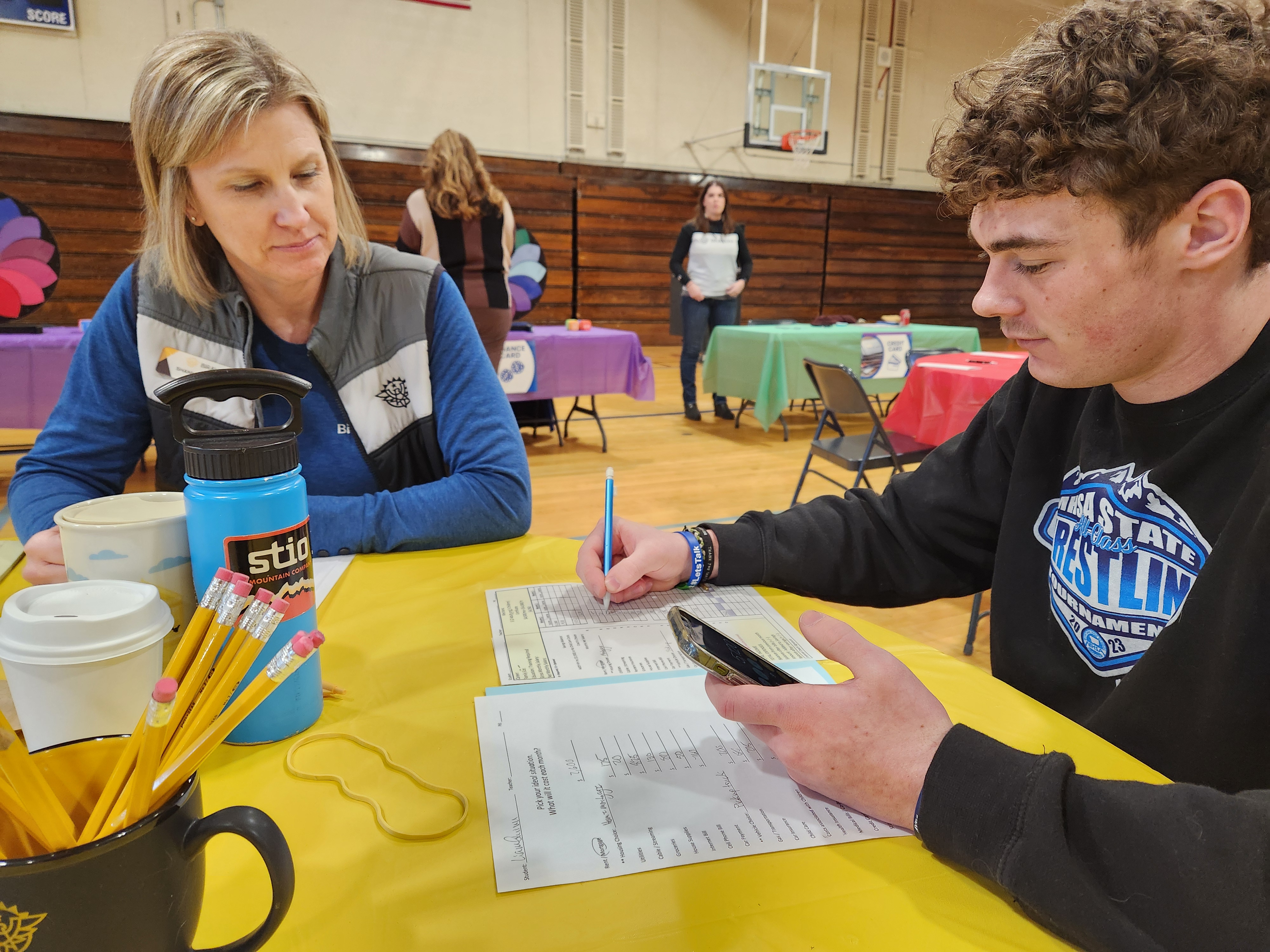 Volunteers coach students on how to balance a budget during a Reality Fair.